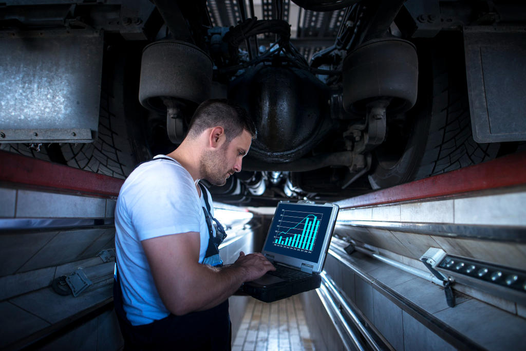Homem em oficina mecânica usando notebook com gráficos, simbolizando a tecnologia aplicada ao remap